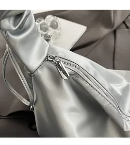 Close-up of smooth metal zipper detail on a silver pleated leather shoulder bag