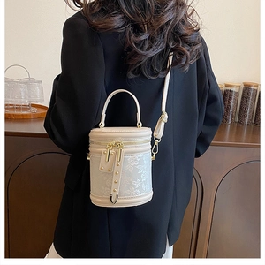 Detail of elegant beige bucket bag with lace pattern and gold hardware on a model