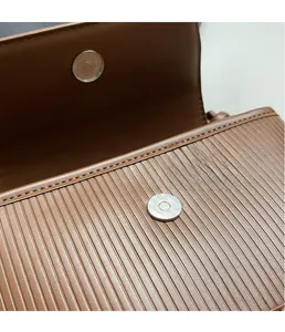Detailed macro view of brown textured leather bag with silver magnetic snap buckle
