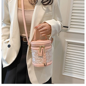 Detail of pink bucket bag with white floral lace embroidery and gold zipper hardware