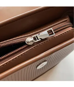 Detail of the smooth metal zipper pull and textured brown leather on this retro crossbody bag