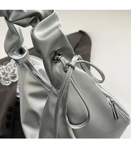 Detail of silver pleated handbag featuring drawstring handle and textured PU leather