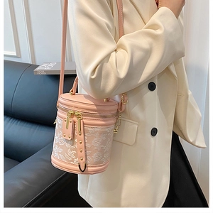 Detail of light pink bucket bag with floral embroidery and golden rivet accents