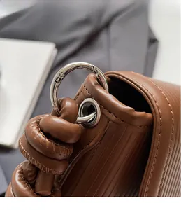 Detail of silver metal ring buckle and woven handle on brown textured leather bag