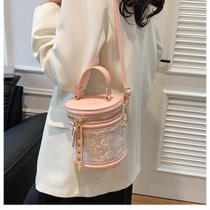 Detailed view of pink leather cylindrical bucket bag with white floral lace embroidery