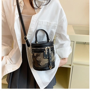 Detail of black leather bucket bag featuring gold butterfly embroidery and metal studs