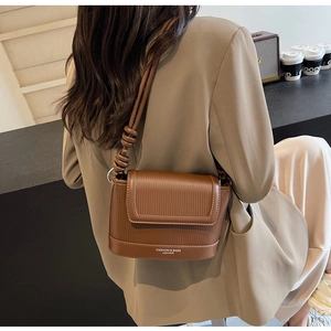 Detail of caramel leather crossbody bag with vertical texture and knotted strap