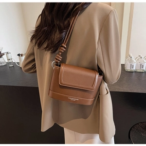 Detail of brown pleated leather crossbody bag with decorative knots and elegant branding