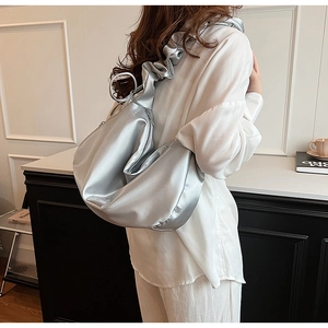 Detail of silver satin cloud shoulder bag featuring textured ruched strap and crescent shape