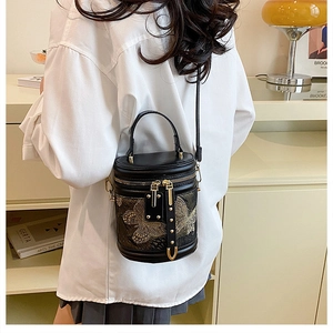 Detail of black cylinder bag featuring intricate gold butterfly embroidery and top handle