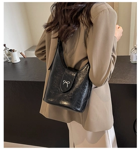 Detail of glossy pleated PU leather crossbody bag with silver metal bow clasp