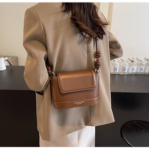 Detail of brown square crossbody bag with mixed textures and knotted leather strap