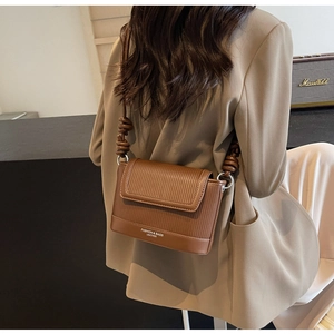 Detail of dark brown leather crossbody bag with vertical stripe embossing and knot strap