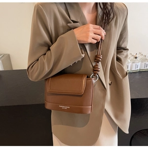 Detail of caramel brown leather crossbody bag with vertical striped embossing and rope strap