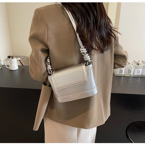 Detail of silver pleated leather shoulder bag with knot strap and metallic brand logo