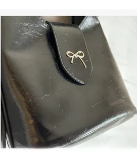 Detail of black leather bucket bag with silver metal bow lock and soft texture