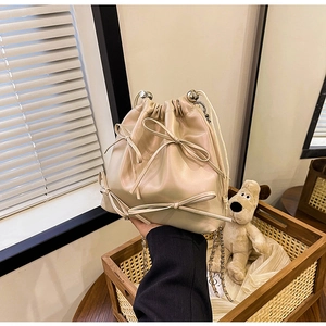 Dettaglio della borsa a secchiello beige con fiocchi e tracolla a catena argento