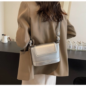 Detail of silver crossbody bag with textured stripes and decorative knotted handle