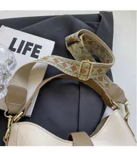 Detail of a chic bicolor shoulder bag with a vintage patterned wide jacquard strap