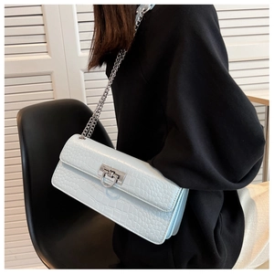 Detailed close-up of light blue crocodile embossed leather bag with silver chain and lock