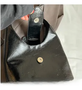 Macro detail of glossy pleated PU leather texture and silver magnetic buckle on bag