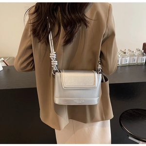 Detail of silver structured crossbody bag with ribbed texture and knotted strap
