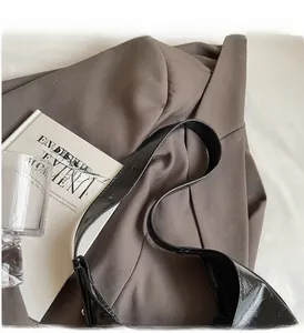 Close-up of black glossy PU leather shoulder bag with durable wide strap and stitching