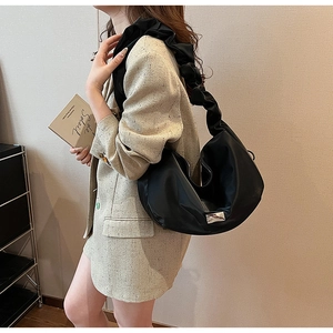 Détail d'un sac à bandoulière plissé noir porté avec un blazer beige chic