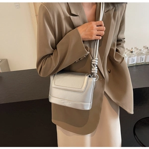 Detail of silver metallic crossbody bag featuring vertical striped embossing and knot strap