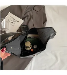 Top view of spacious black glossy bucket bag interior with phone and cosmetics