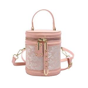 Pink cylinder bucket bag with embossed white floral patterns and gold hardware