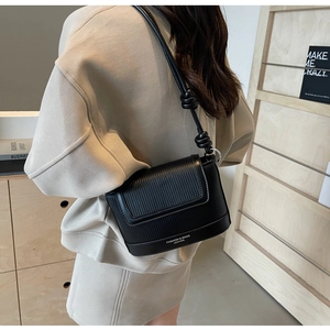 Detail of black ribbed leather shoulder bag with a unique knotted strap design