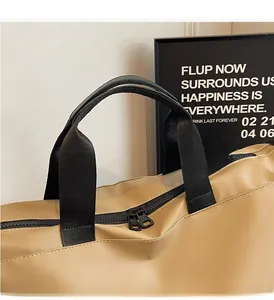 Detail of durable black handles and smooth dual zippers on khaki travel duffel bag