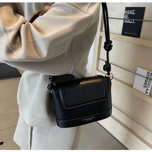 Detail of black crossbody bag with vertical stripe texture and knotted shoulder strap
