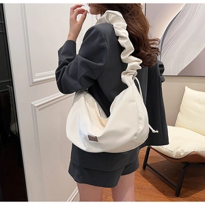Détail de la large bandoulière froncée sur un sac hobo beige pour les trajets