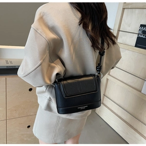 Detailed view of black vintage crossbody bag with vertical stripe embossing and strap knot