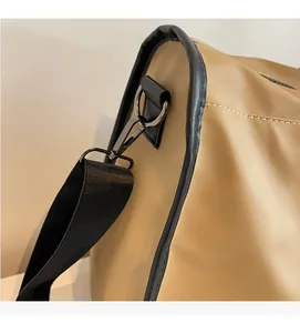 Close-up of the gun-black metal hook and nylon shoulder strap on a khaki gym bag
