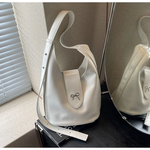 Detailed macro view of white leather hobo bag with a silver bow buckle and wide strap