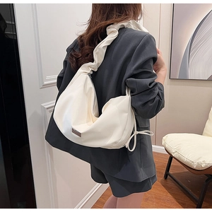 Détail du sac à bandoulière plissé blanc avec large sangle et logo en métal
