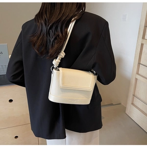 Detail of cream white crossbody bag with vertical pleated texture and knotted shoulder strap