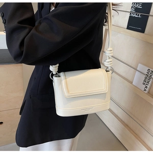 Detail of white leather shoulder bag with vertical stripe texture and knotted strap
