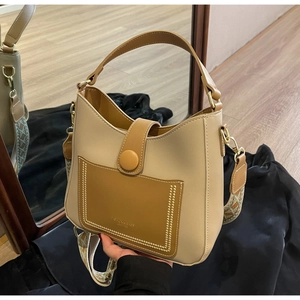 Detail of beige and brown bucket bag with leather pocket and patterned woven shoulder strap