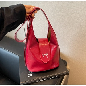 Detail of red embossed leather bucket bag featuring a silver bow metal decoration