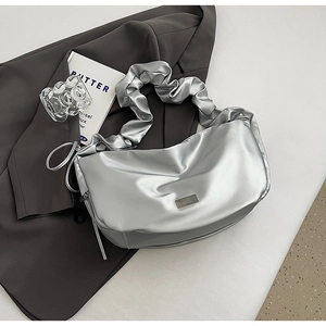 Détail du sac à bandoulière argenté plissé avec texture métallique et plaque de marque