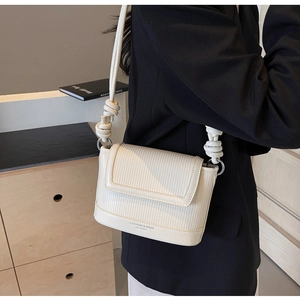Detail of off-white leather crossbody bag with vertical embossing and knotted strap