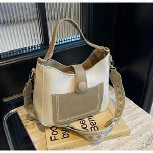 Detail of color-block bucket bag featuring ethnic jacquard strap and leather texture