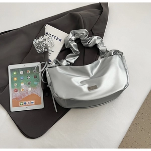 Détail du sac à bandoulière plissé argenté avec fini métallique et bandoulière nuage sur costume