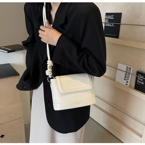 Detail of cream striped leather crossbody bag with a white knotted thick rope strap