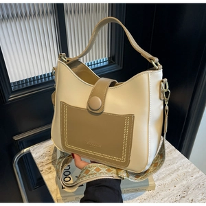 Detail of beige leather bucket bag with brown pocket and ethnic embroidery strap