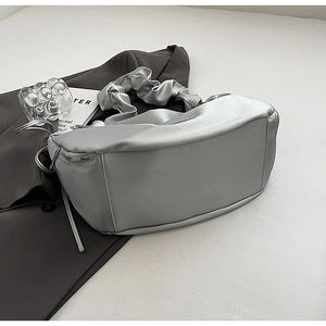 Gros plan d'un sac plissé argenté avec détail de fermeture éclair sur tissu gris